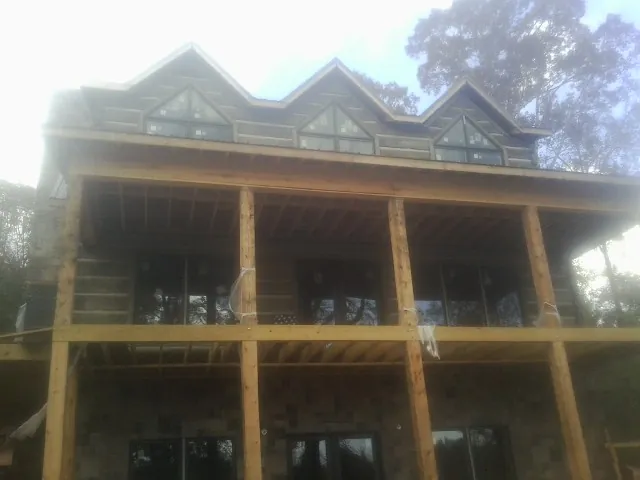 Dormers and porch framing on a large log home under construction — Roof Coating work by our crew in Vinton