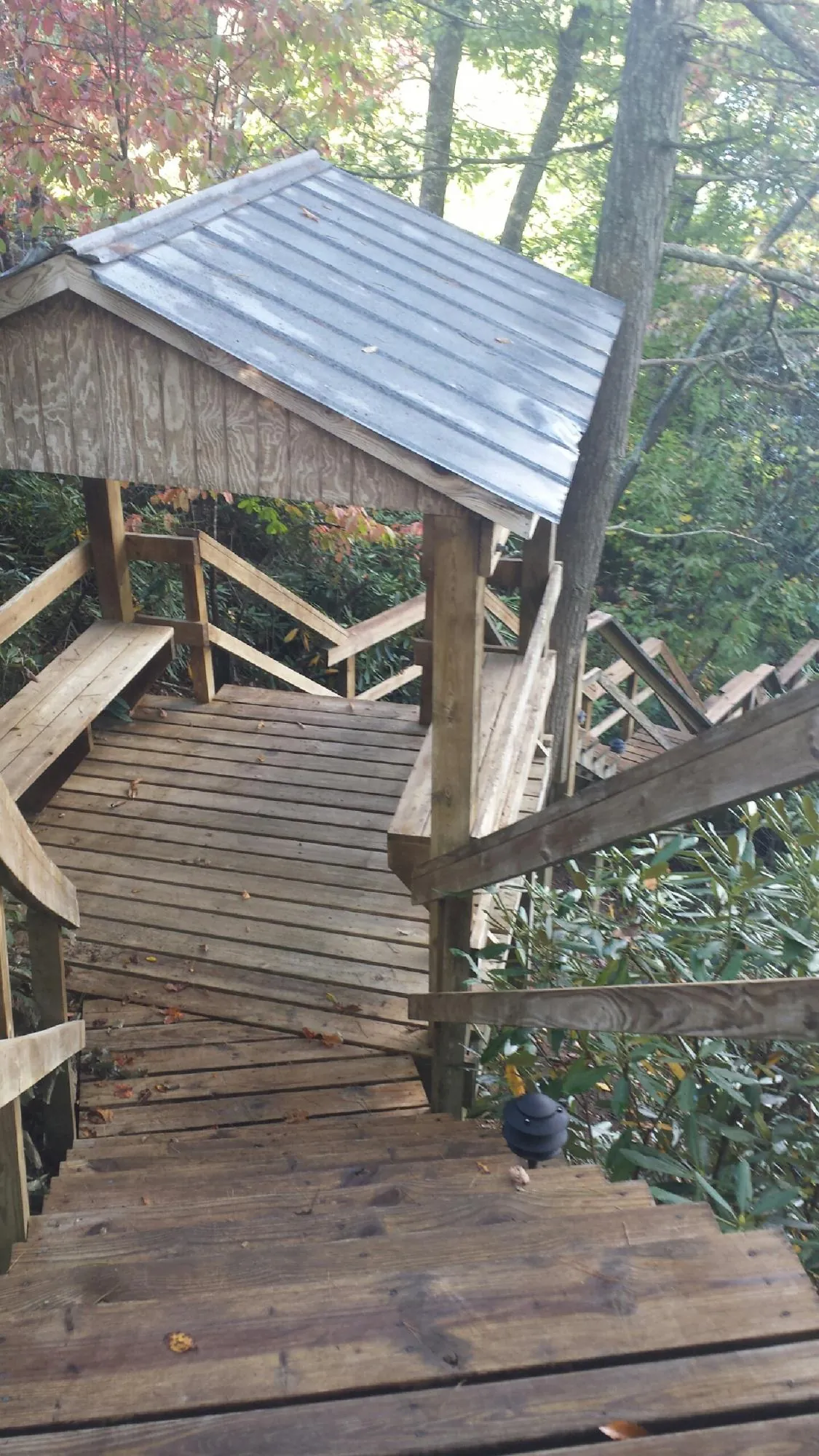Metal roofed shelter over wooden steps on a wooded walkway — Skylight Repair & Installation work by our crew in Vinton